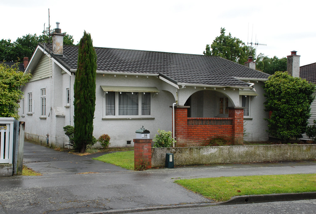 Single-storey brick and stucco New Zealand bungalow on a quiet suburban street